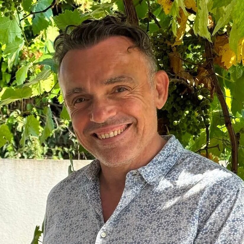 Frédéric Barozzi, souriant, sous une treille de vigne